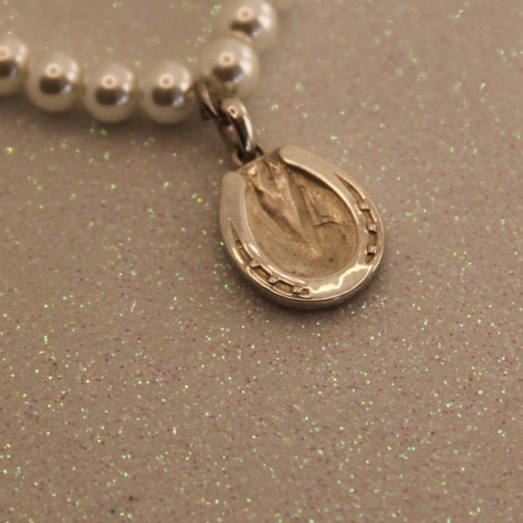 Hoofprint pendant on a string of pearls in the sunlight